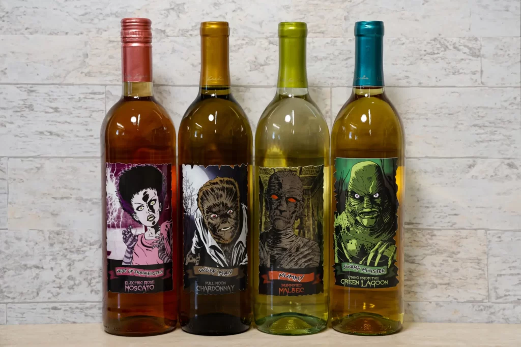 Wine bottles lined up with wine label designs featuring monster movie characters such as the wolf man, a mummy, and the swamp monster